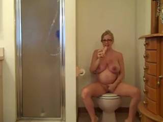 Femme enceinte qui s'offre un peu de plaisir avec son jouet dans les toilettes